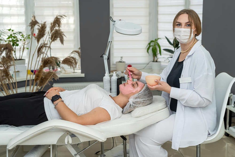 Aesthetician applying a calming facial mask to a client at a Scarborough med spa, reflecting the importance of self-care and community wellness.