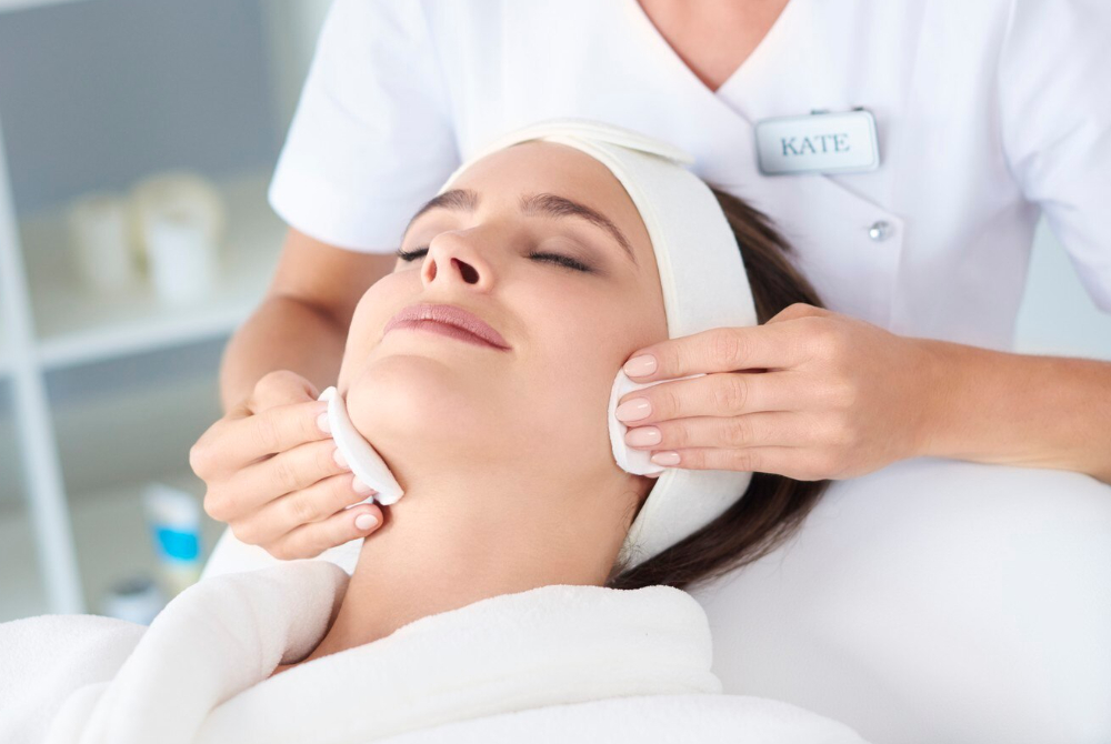 Aesthetician giving a relaxing facial treatment to a woman.