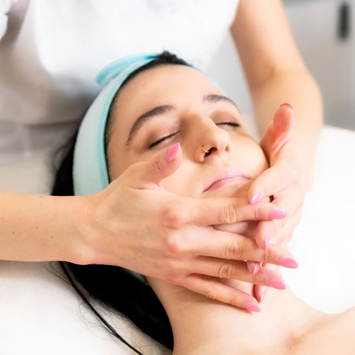 Skincare specialist gently massaging a client’s face during a treatment for relaxation and improved skin health.